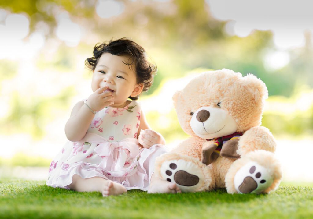 Baby mit Teddy auf einer Wiese